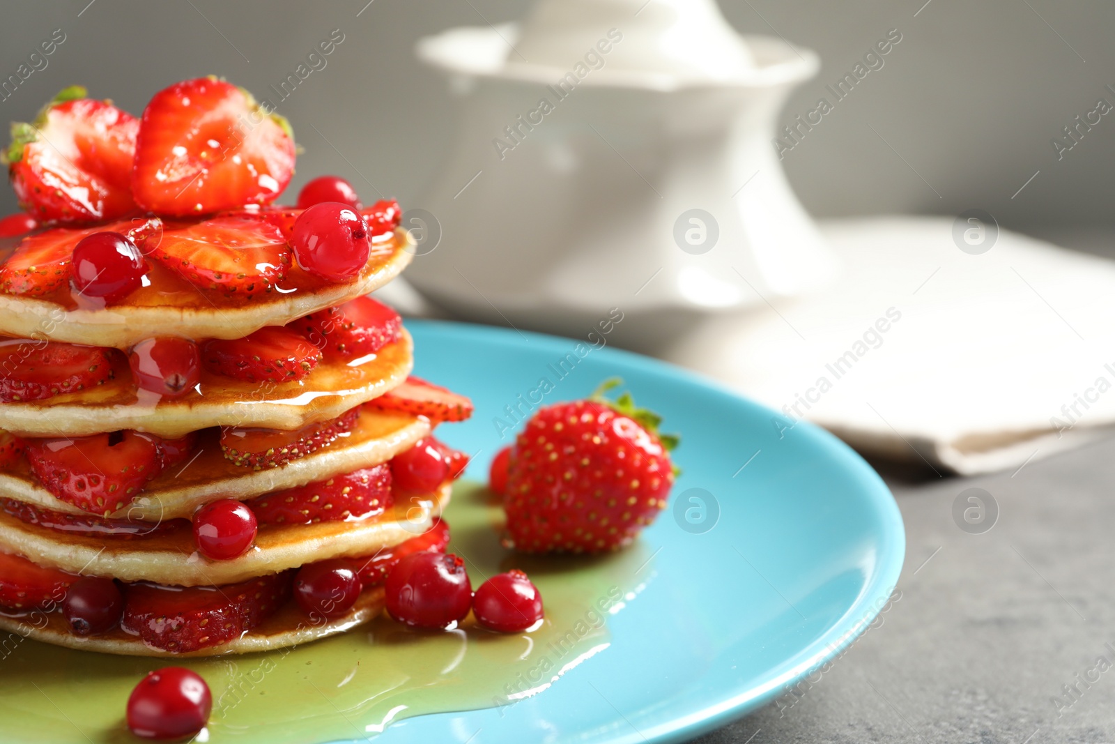 Photo of Tasty pancakes with berries and honey on plate, closeup