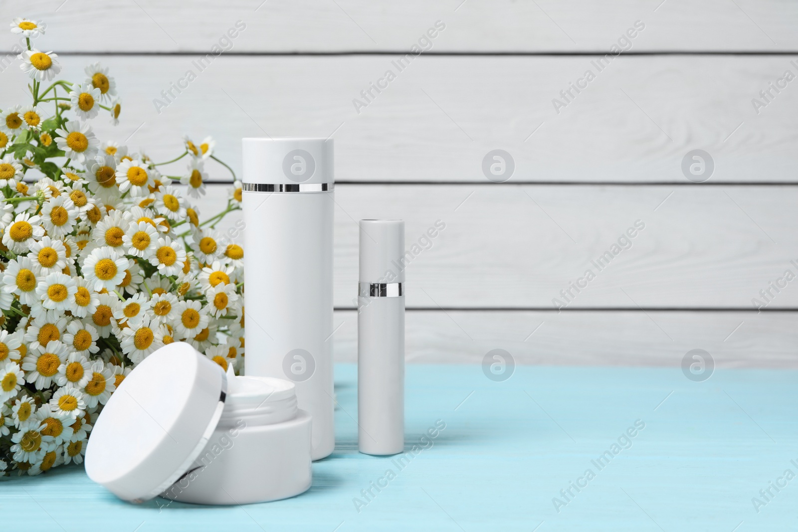 Photo of Composition with chamomile flowers and cosmetic products on wooden table, space for text