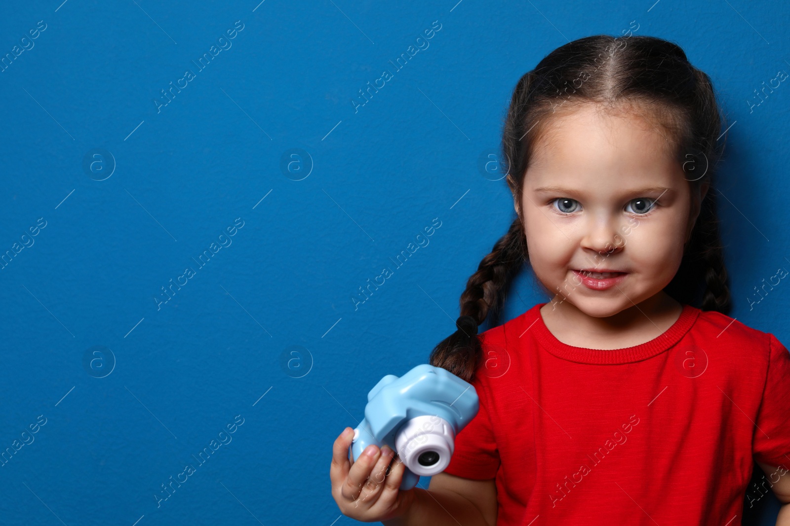 Photo of Little photographer with toy camera on blue background. Space for text