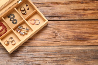 Photo of Jewelry box with many different accessories on wooden table, top view. Space for text
