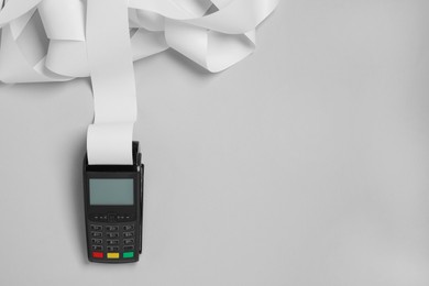 Photo of Payment terminal with thermal paper for receipt on light grey background, top view. Space for text