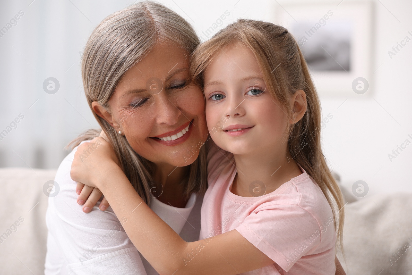 Photo of Happy grandmother hugging her granddaughter at home