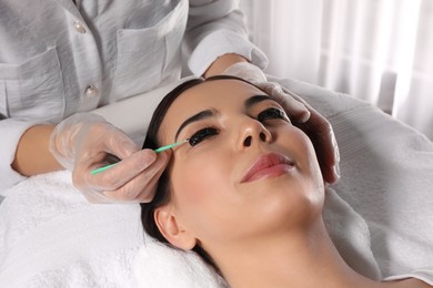 Photo of Young woman undergoing eyelash lamination and tinting in salon