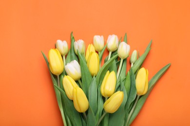 Bouquet of beautiful yellow tulips on orange background, top view