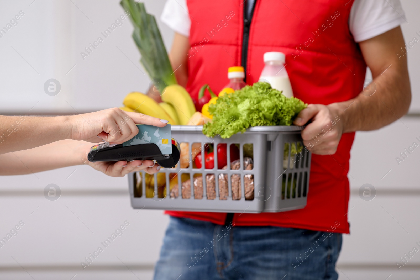 Photo of Customer using bank terminal to pay for food delivery indoors, closeup