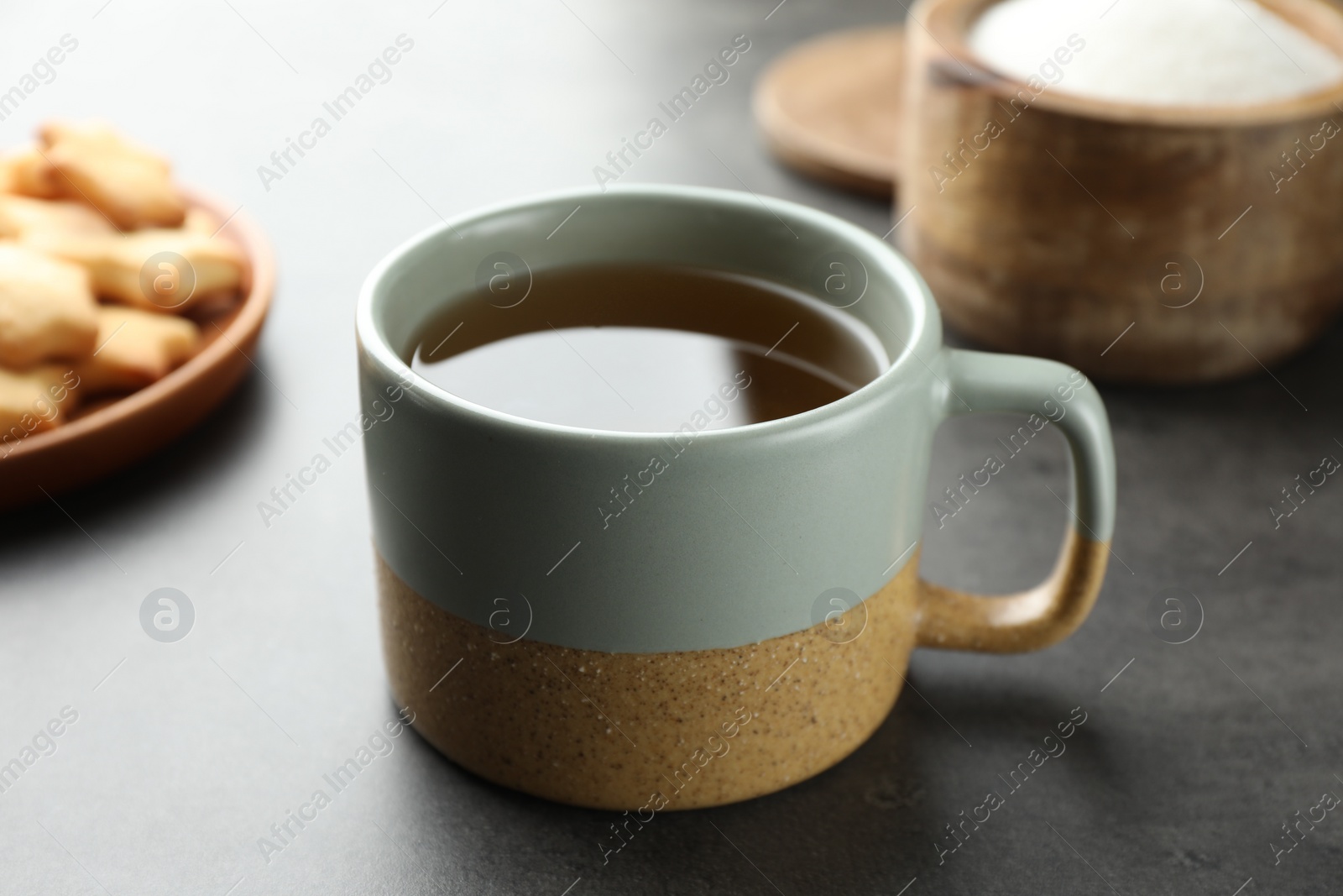 Photo of Cup of aromatic tea on grey table, closeup