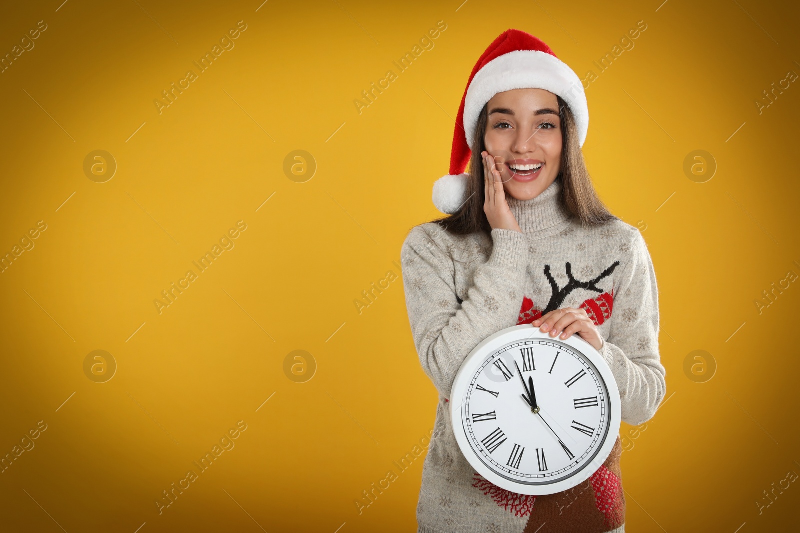 Photo of Woman in Santa hat with clock on yellow background, space for text. Christmas countdown