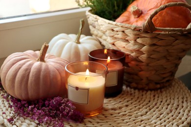 Photo of Wicker basket with beautiful heather flowers, pumpkins and burning candles near window indoors, closeup