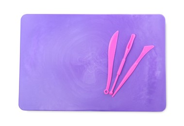Photo of Purple board with tools for plasticine on white background, top view