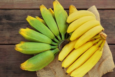 Different sorts of bananas on wooden table, flat lay