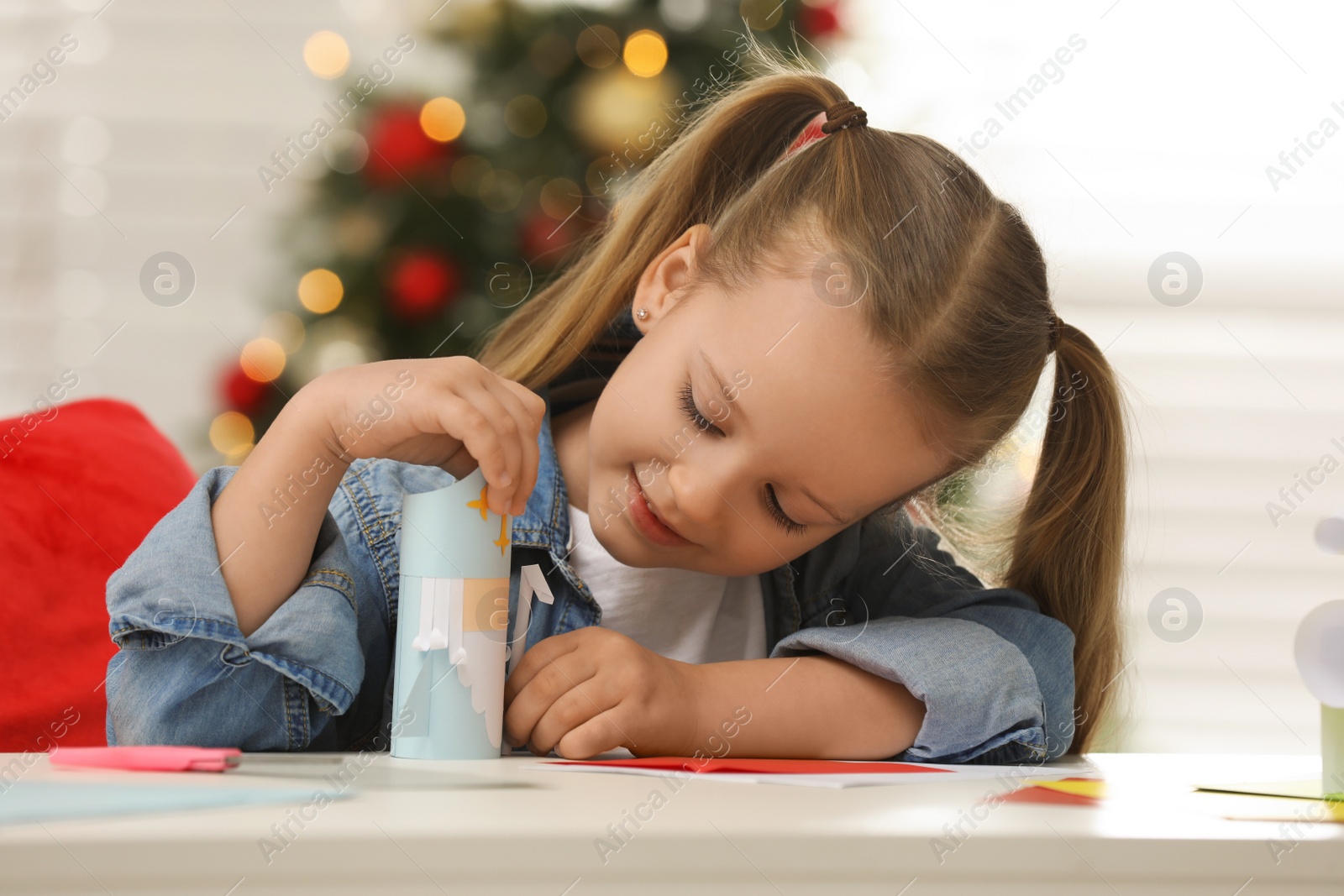 Photo of Cute little girl with paper Saint Nicholas toy at home