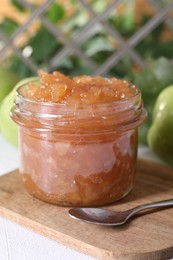 Photo of Glass jar of delicious apple jam on white table, closeup