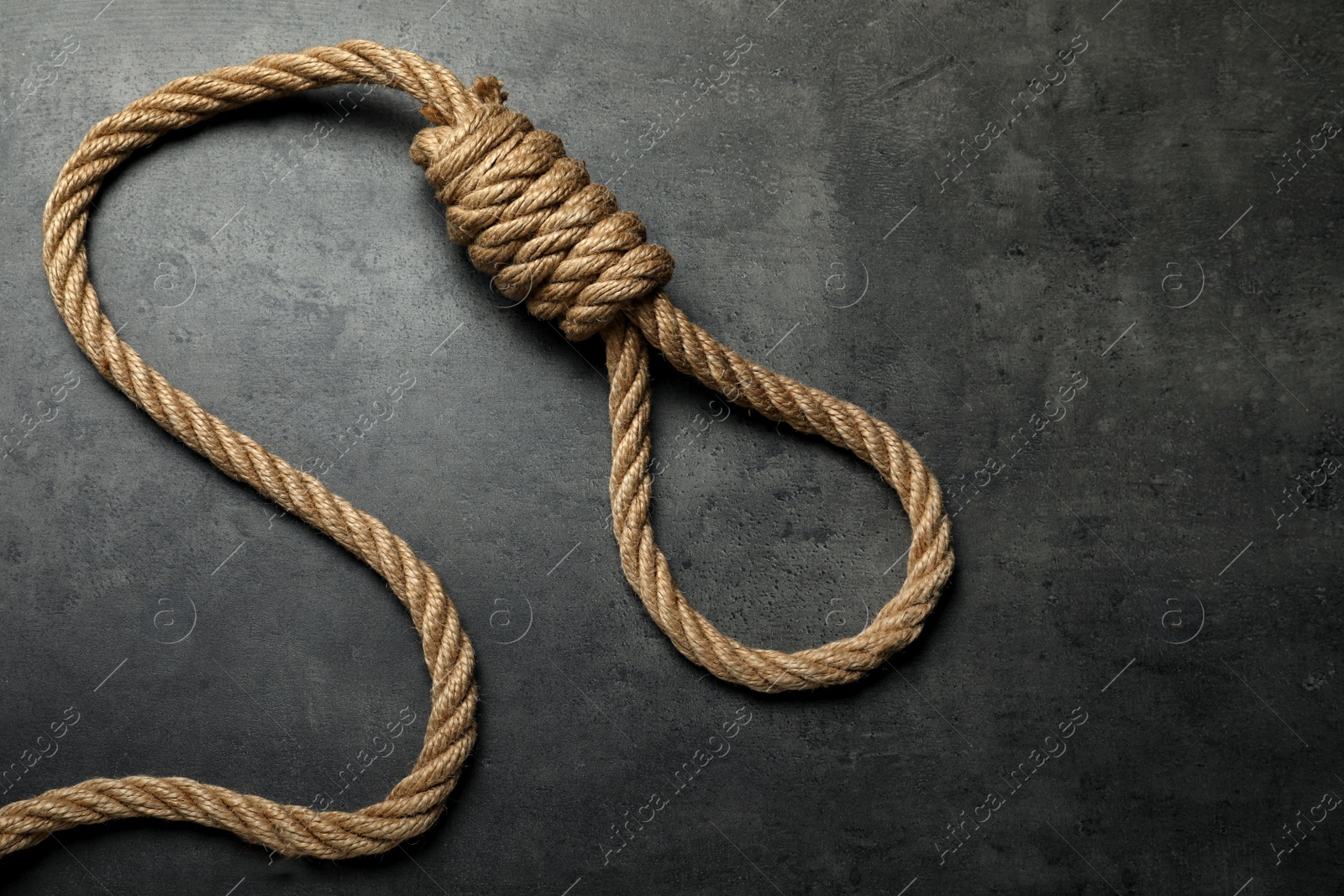 Photo of Rope noose with knot on grey table, top view. Space for text