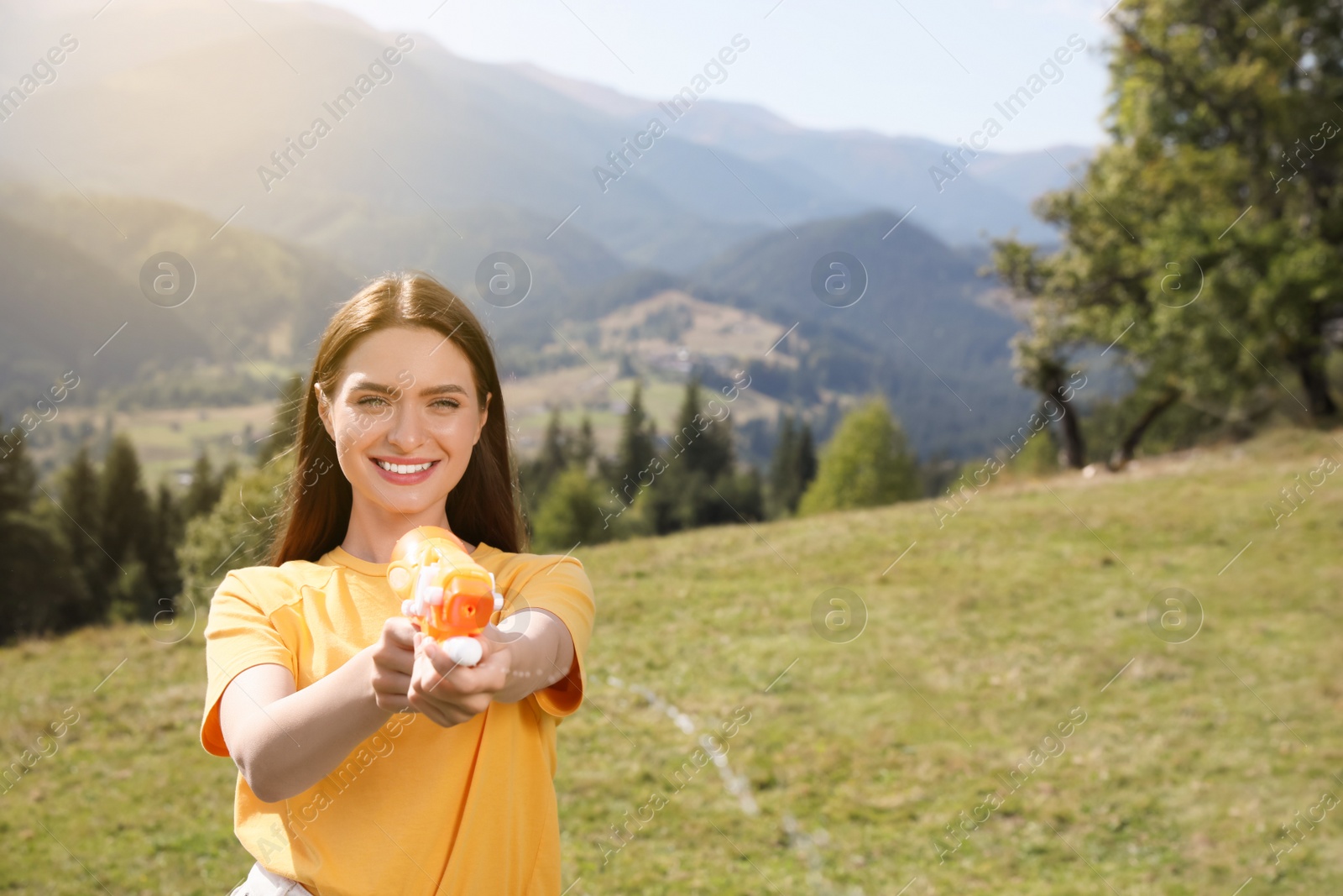 Photo of Happy woman with water gun having fun in mountains on sunny day