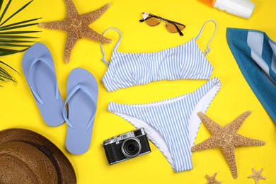 Photo of Flat lay composition with swimsuit and beach accessories on yellow background
