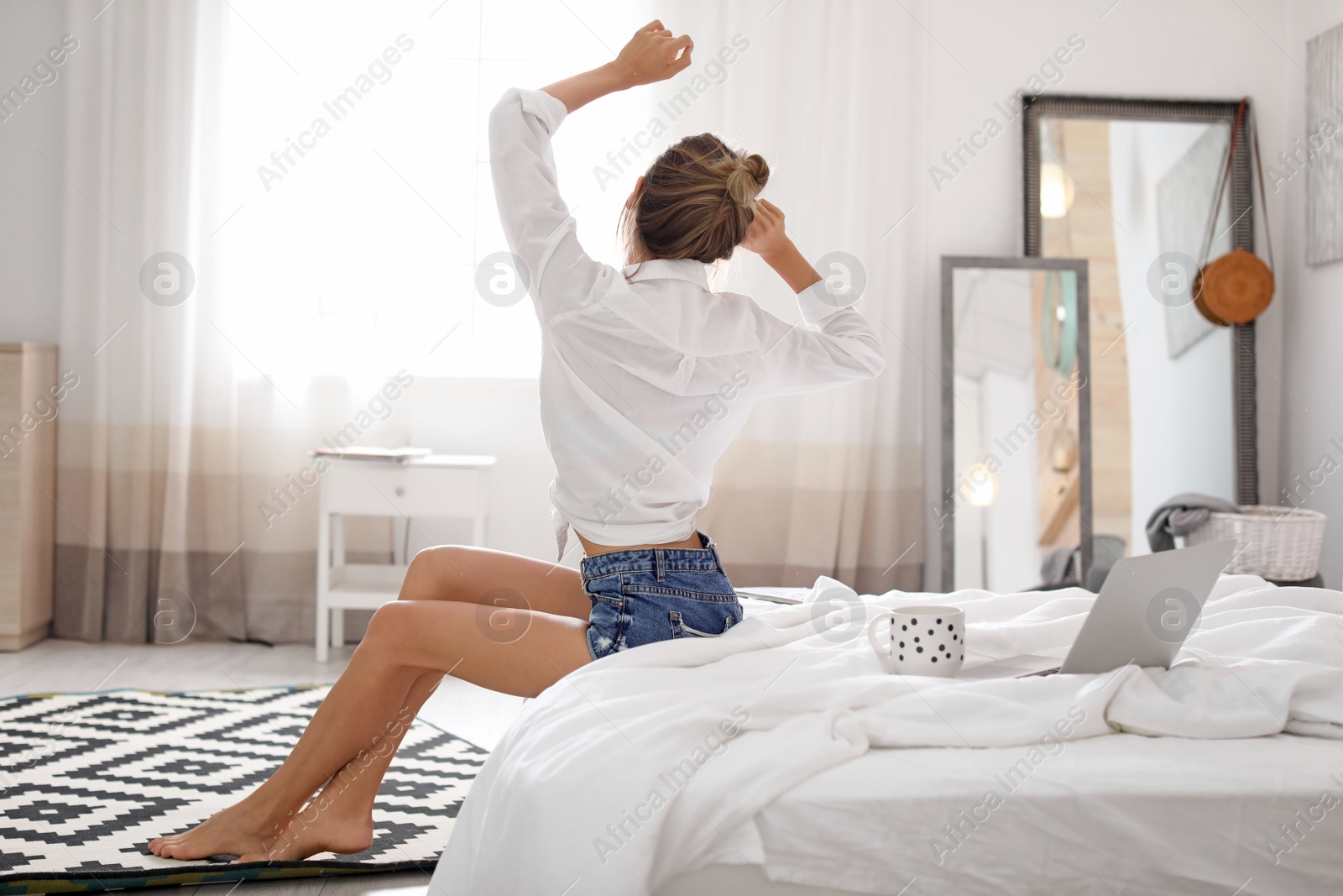 Photo of Young happy woman stretching on bed at home. Lazy morning