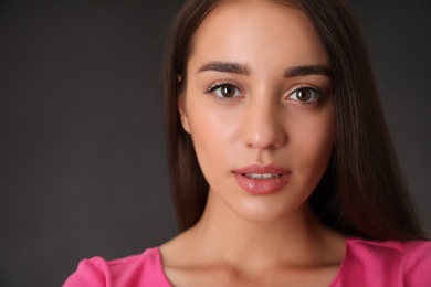 Portrait of beautiful young woman on dark grey background, closeup