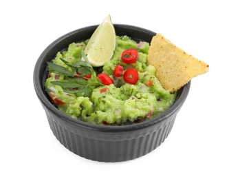 Photo of Delicious guacamole served with nachos chips, lime and pepper isolated on white