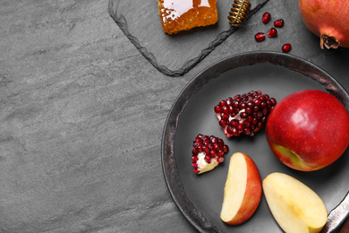 Photo of Honey, apples and pomegranates on black table, flat lay with space for text. Rosh Hashanah holiday