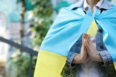 Photo of Woman holding national flag of Ukraine outdoors, closeup. Space for text