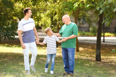 Photo of Man with son and elderly father in park on sunny day