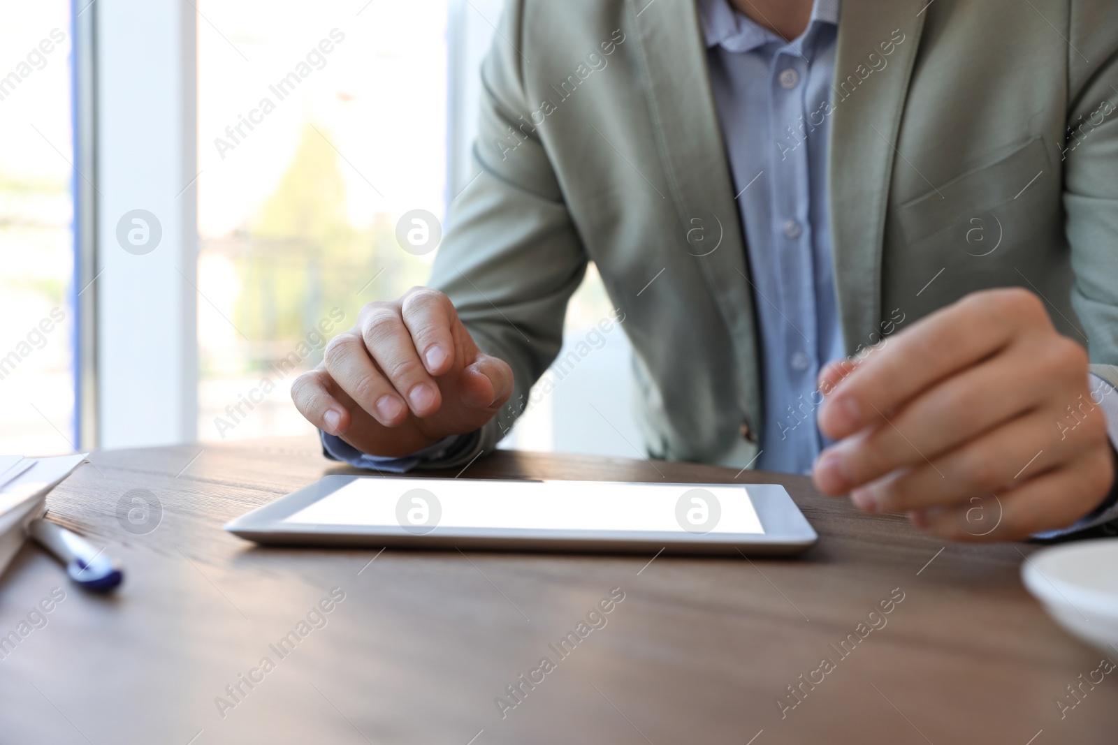 Photo of Businessman working with modern tablet at wooden table in office, closeup