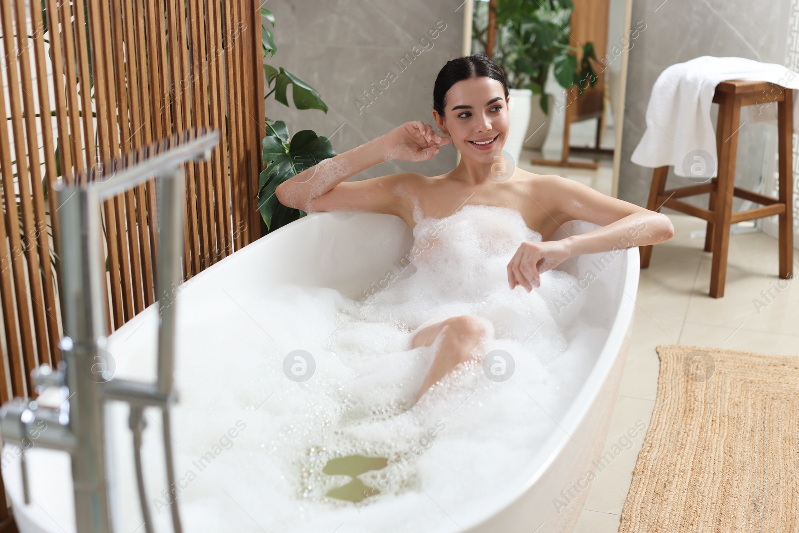 Photo of Beautiful young woman taking bubble bath at home