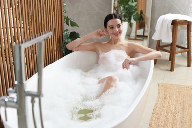 Beautiful young woman taking bubble bath at home