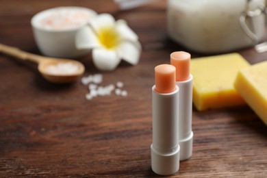Photo of Hygienic lipsticks with natural beeswax component on wooden table. Space for text