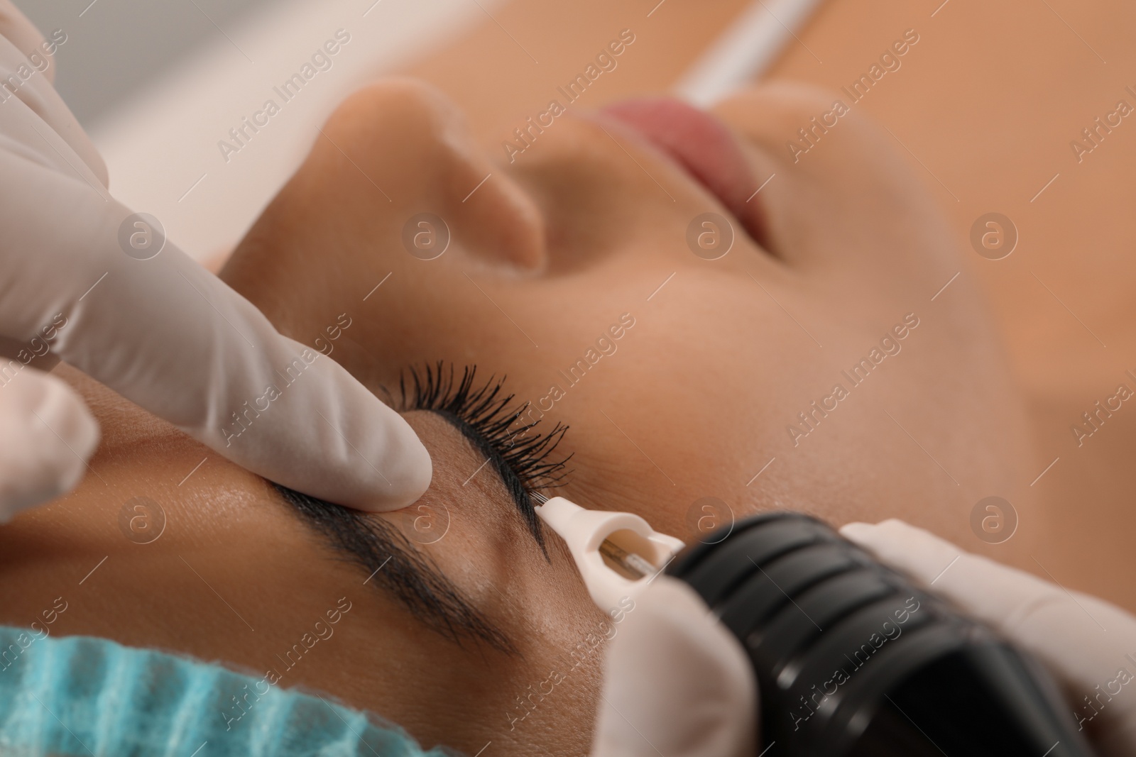 Photo of Young woman undergoing procedure of permanent eyeliner makeup, closeup