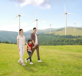 Image of Happy family with child and view of wind energy turbines on sunny day