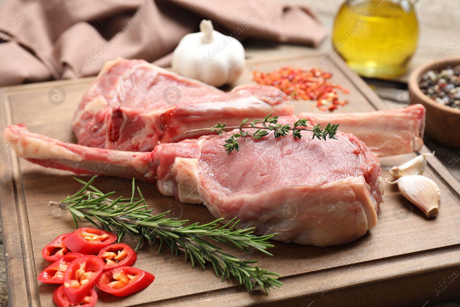 Photo of Fresh tomahawk beef cuts and spices on wooden board, closeup