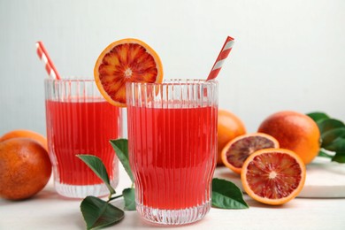 Photo of Tasty sicilian orange juice and fruits on white wooden table