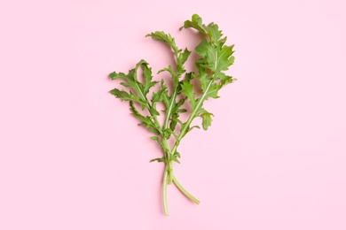 Photo of Fresh arugula on light pink background, flat lay