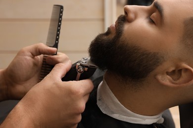 Photo of Professional hairdresser working with client in barbershop, closeup