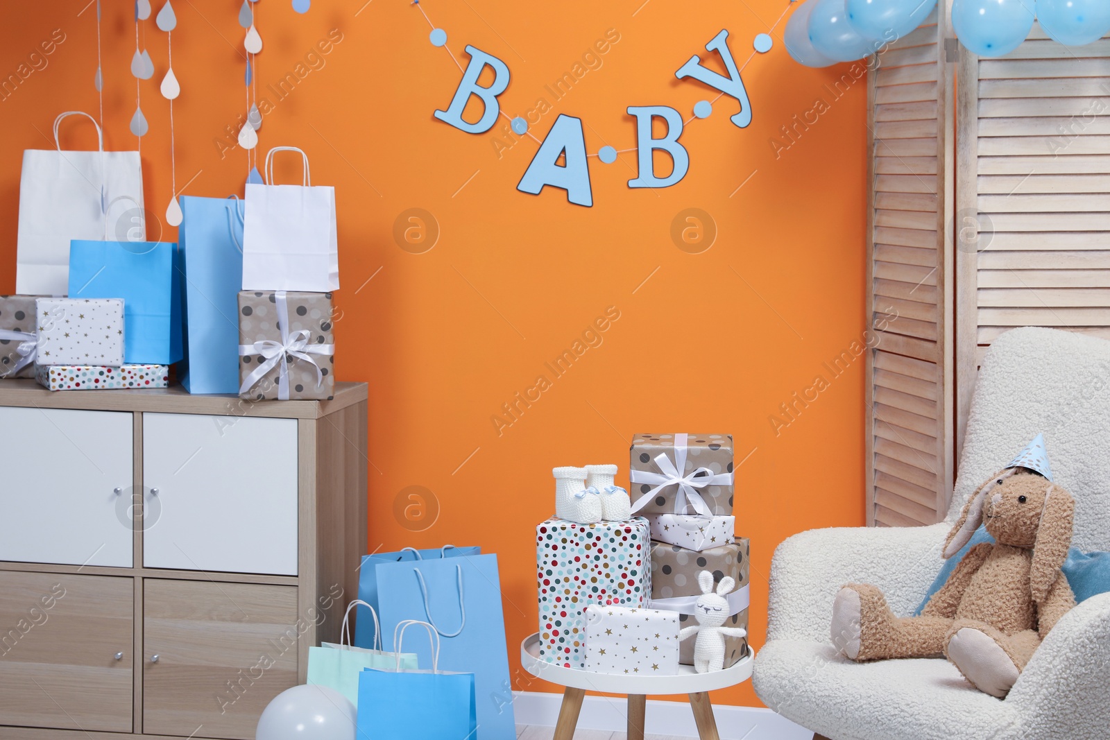 Photo of Baby shower party. Festive decor, booties, toys and gift boxes in stylish room