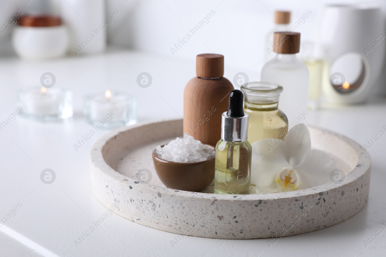 Photo of Essential oils, sea salt and orchid flower on white table in bathroom, closeup. Space for text