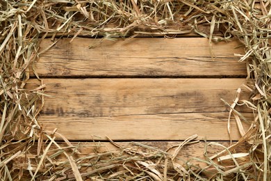 Photo of Frame made of dried hay on wooden background, top view. Space for text