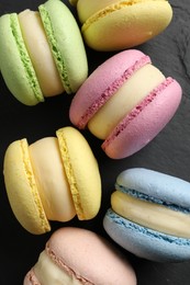 Photo of Delicious colorful macarons on black table, flat lay