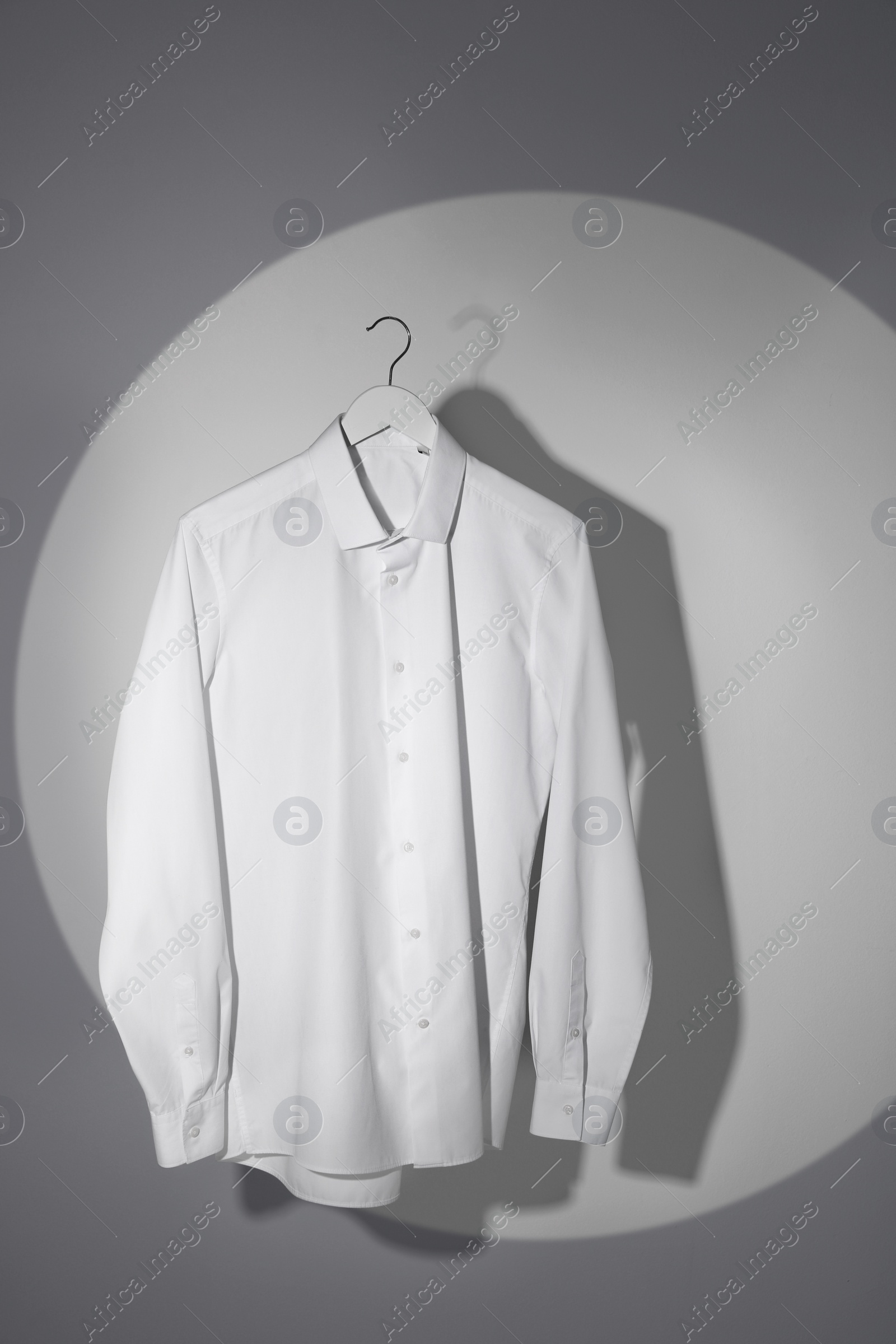 Photo of Stylish men's shirt hanging on light wall