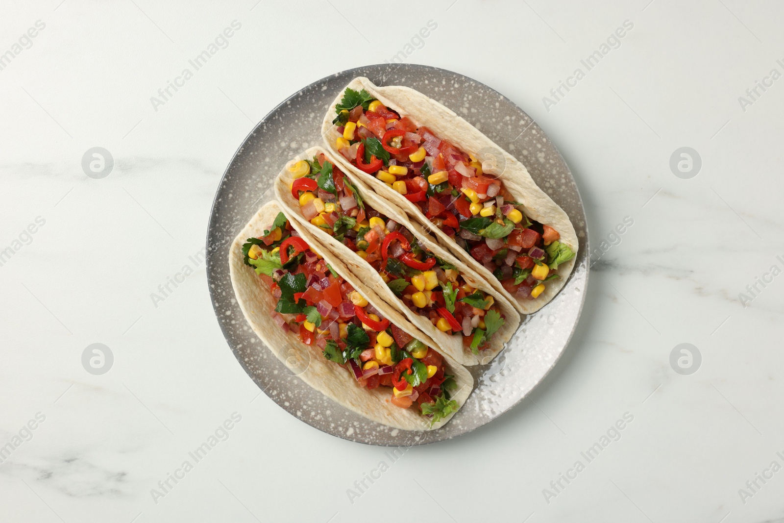 Photo of Tasty tacos with vegetables on white marble table, top view