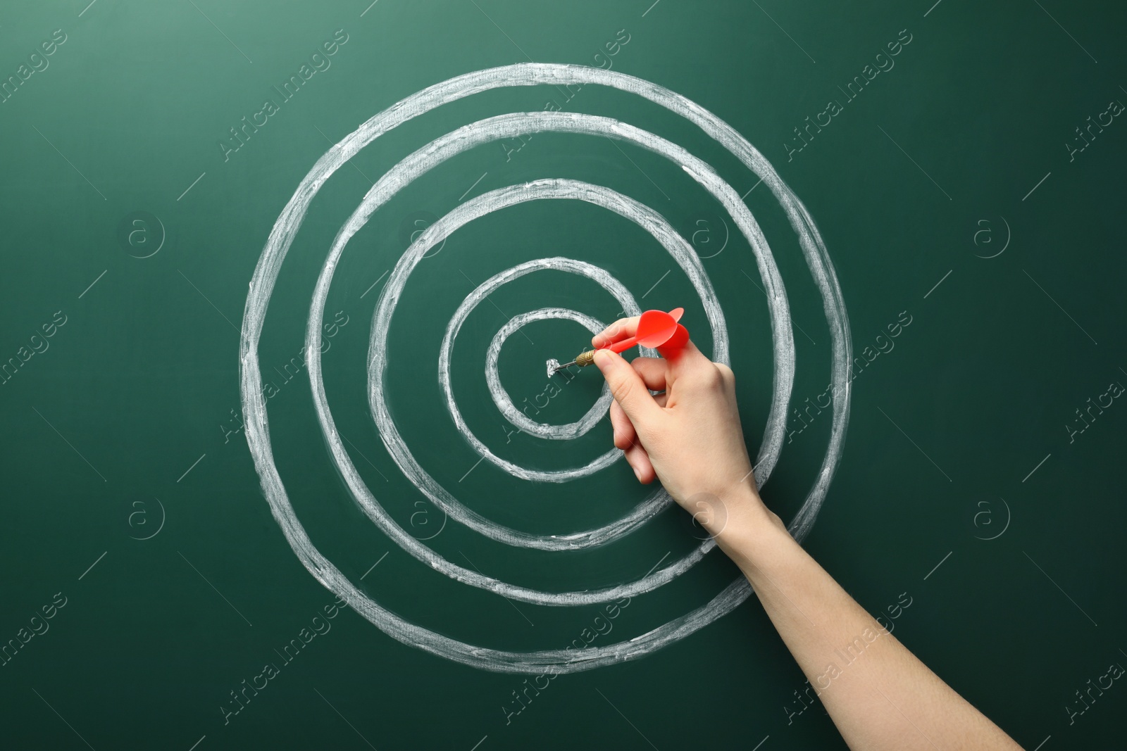 Photo of Woman with dart and chalk drawing of target  on green background, closeup. Victory concept