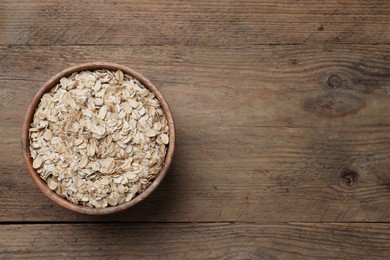 Photo of Bowl of oatmeal on wooden table, top view. Space for text