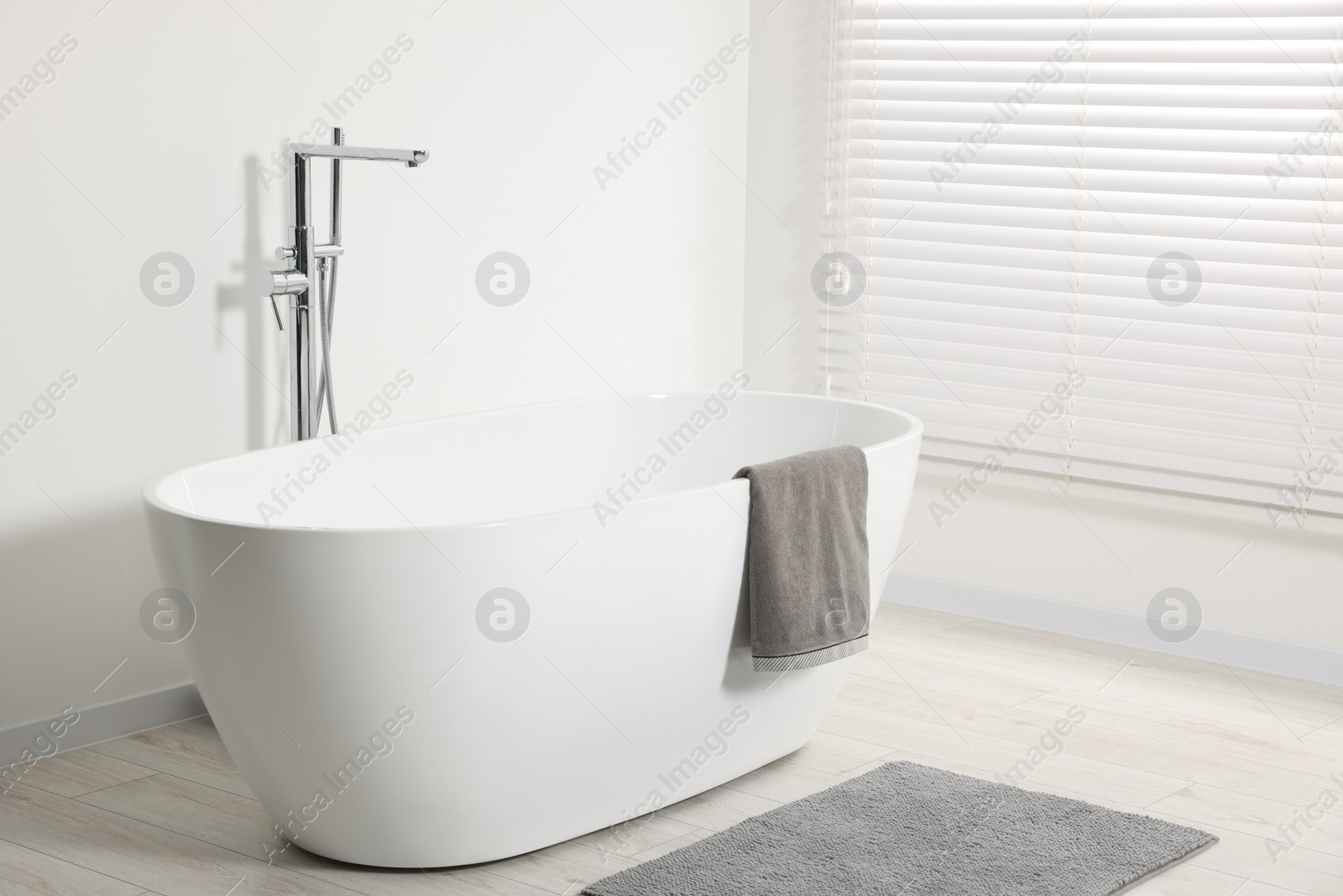 Photo of Stylish bathroom interior with ceramic tub and terry towel