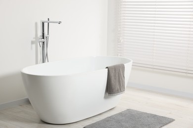 Photo of Stylish bathroom interior with ceramic tub and terry towel