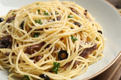 Delicious pasta with anchovies, olives and parmesan cheese on wooden table, closeup