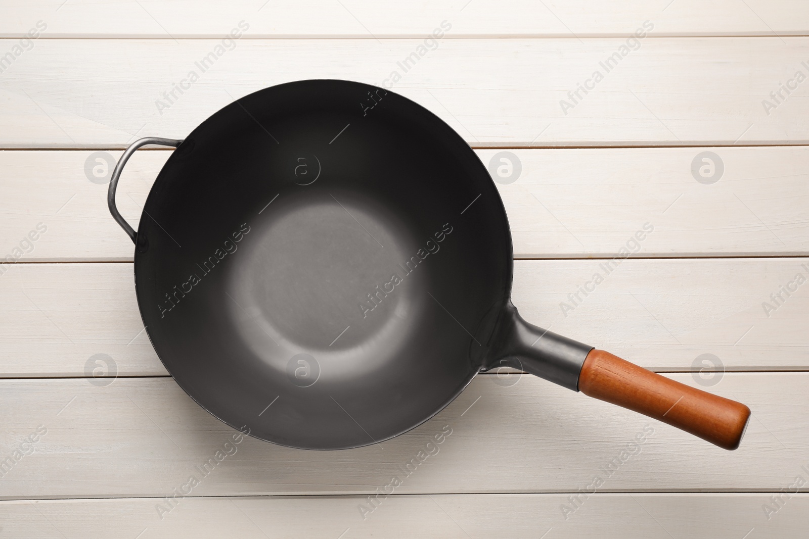 Photo of Empty iron wok on white wooden table, top view. Chinese cookware
