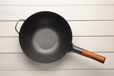 Empty iron wok on white wooden table, top view. Chinese cookware