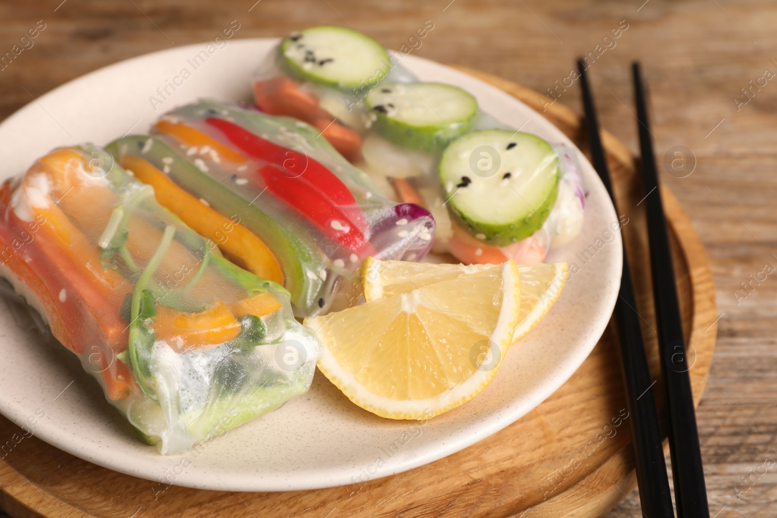 Photo of Delicious rolls wrapped in rice paper on wooden table, closeup