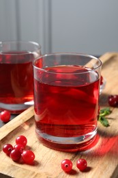 Photo of Tasty refreshing cranberry juice and fresh berries on wooden tray